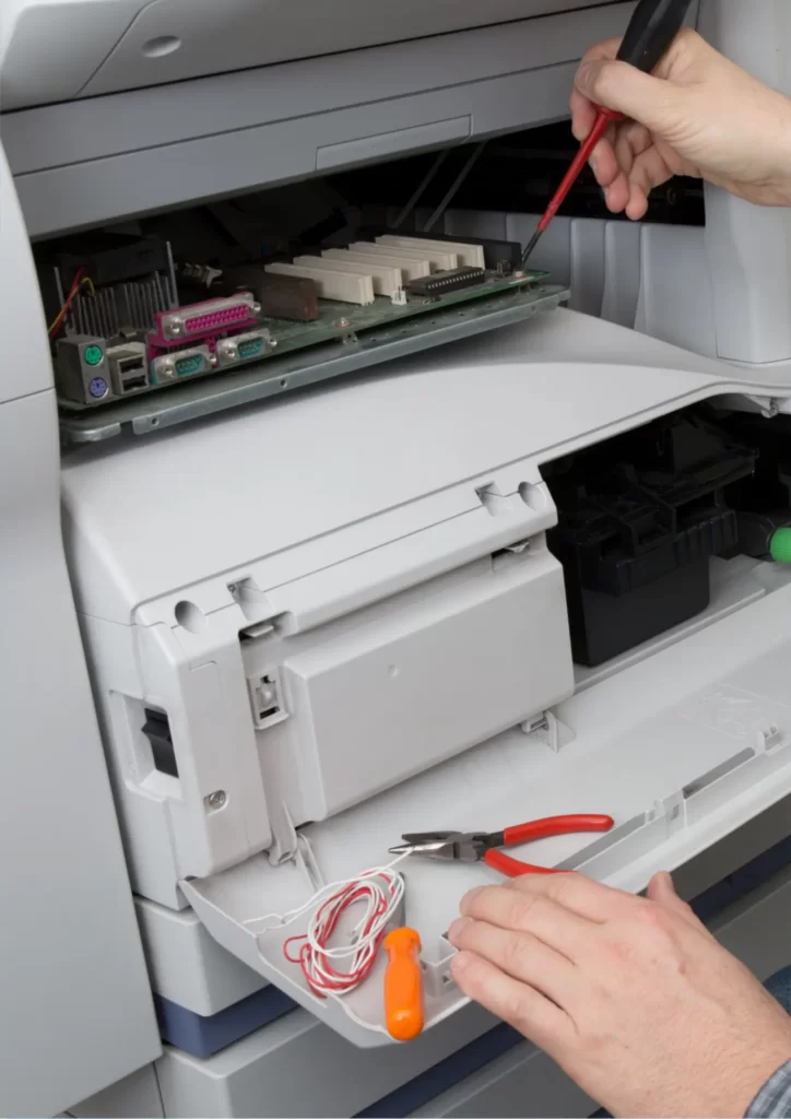 Experienced technician repairing an office printer in a workplace