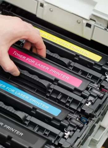 Technician replacing printer toner cartridge in a business office setting.